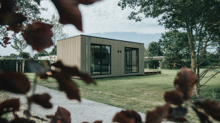 Moderna cabaña de madera rodeada de árboles en Holiday park De Klepperstee, Países Bajos.