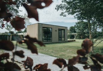 Modern lodgehuis met grote ramen op grasveld, bij Holiday park De Klepperstee in Nederland.