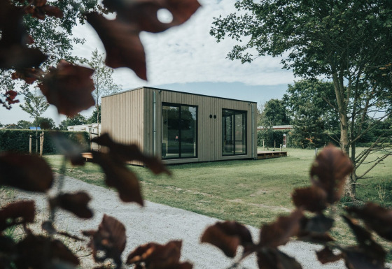 Modern lodgehuis met grote ramen op grasveld, bij Holiday park De Klepperstee in Nederland.