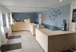 Receptionen på Ballum Camping i Syddanmark, med moderne indretning, trædisk og vægdekorationer.