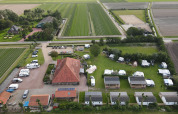 Luchtfoto van Camping de Tulpenweide in Noord-Holland, Nederland, met stacaravans, tenten en velden.