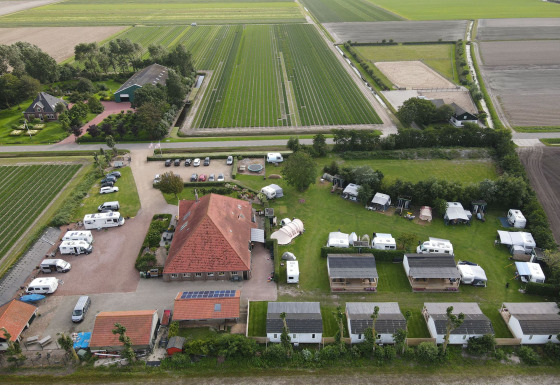 Luchtfoto van Camping de Tulpenweide in Noord-Holland, Nederland, met stacaravans, tenten en velden.