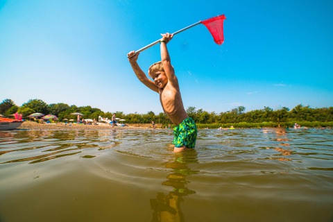 Jongen speelt met een schepnet in het water bij Papillon Country Resort, een vakantiepark in Overijssel.