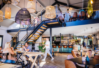 Modern restaurantinterieur met houten meubels, sfeerverlichting en gasten in Papillon Country Resort.