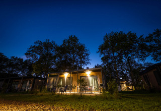 Verlichte houten huisjes bij nacht in Papillon Country Resort, vakantiepark omringd door bomen in Overijssel.