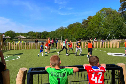 Kinderen spelen voetbal op een kunstgrasveld bij Papillon Country Resort, met groene natuur op de achtergrond.