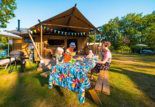 Gezin geniet van een zomerse maaltijd buiten bij een glampingtent op Papillon Country Resort, Overijssel.