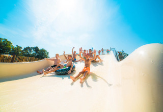 Kinderen glijden lachend van een waterglijbaan in het Papillon Country Resort in Overijssel, Nederland.