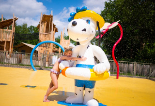 Een meisje knuffelt een groot hondenbeeld met gele zwemband bij het waterspeelpark in Papillon Country Resort.
