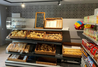 Bakery-afdeling in een winkel bij Papillon Country Resort, met broden, broodjes en sapjes op rekken.