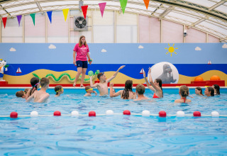 Kinderen spelen in overdekt zwembad met kleurrijke decoratie in Papillon Country Resort, Overijssel.