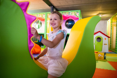 Kind speelt vrolijk op kleurrijk speeltoestel in binnenspeeltuin van Papillon Country Resort, Overijssel.
