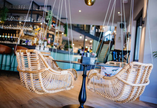 Hippe houten schommelstoelen aan een ronde tafel in een modern café bij Papillon Country Resort.