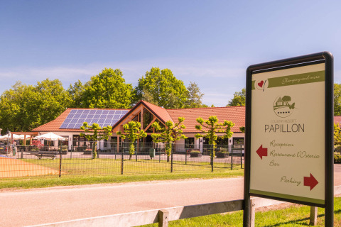 Zicht op het hoofdgebouw van Papillon Country Resort in Overijssel met zonnepalen en bewegwijzering.