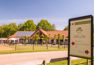 Zicht op het hoofdgebouw van Papillon Country Resort in Overijssel met zonnepalen en bewegwijzering.