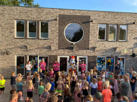 Kinderen en gezinnen verzamelen zich buiten voor een optreden met een mascotte bij Papillon Country Resort.