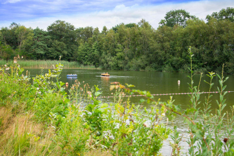 Rustig meer bij Papillon Country Resort in Overijssel, Nederland, met opblaasboten en omringend groen bos.