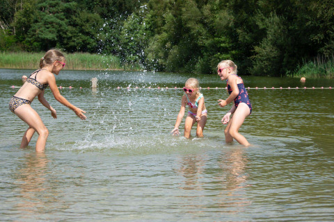 Drie kinderen spelen en spetteren vrolijk in het ondiepe water bij Papillon Country Resort in Overijssel.