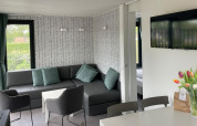 Salón moderno en Bungalow Cottage Prestige en Papillon Country Resort, con sofá, TV y flores de tulipán.