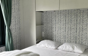 Dormitorio en Bungalow Cottage Prestige en Papillon Country Resort con papel tapiz moderno y cortina verde.