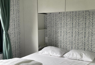 Slaapkamer in Bungalow Cottage Prestige in Papillon Country Resort met modern behang en groene gordijn.