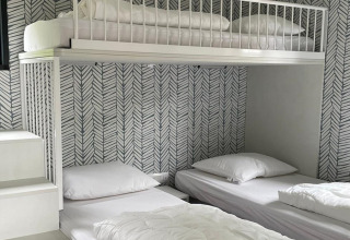 Moderne, compacte slaapkamer met hoogslaper en twee aparte bedden in Bungalow Cottage Prestige, Nederland.