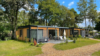 Dos modernas casas tiny house Bungalow Cottage Prestige con fachada de madera y terraza en zona arbolada.