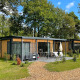 To moderne Bungalow Cottage Prestige tiny houses med træfacade, store vinduer og terrasse i skovområde.
