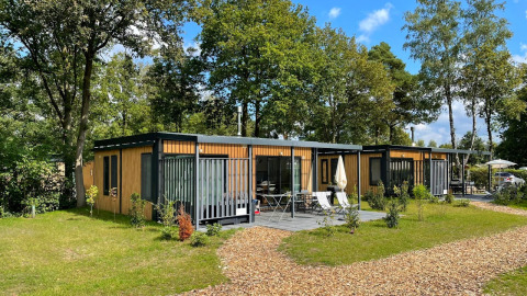 Twee moderne Bungalow Cottage Prestige tiny houses met houten buitenzijde en terras in een groene omgeving.