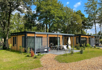 Twee moderne Bungalow Cottage Prestige tiny houses met houten buitenzijde en terras in een groene omgeving.