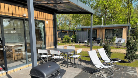 Terraza exterior con mesa, sillas, tumbonas y barbacoa en Bungalow Cottage Prestige del Papillon Country Resort.