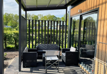 Buitenterras met moderne stoelen aan Bungalow Cottage Prestige op Papillon Country Resort in Nederland.