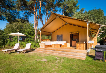 En komfortabel safaritelthytte på Papillon Country Resort i Holland, med terrasse, solsenge og grill.