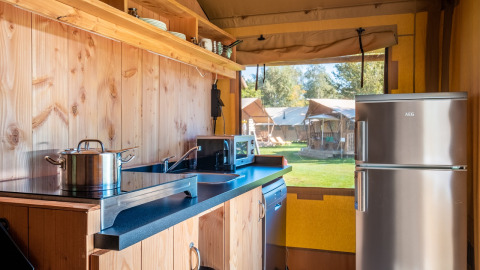 Køkkenområde i Safari telt Comfort på Papillon Country Resort, komplet med apparater og udsigt udenfor.