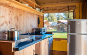 Área de cocina en la tienda Safari Comfort en Papillon Country Resort, con electrodomésticos y vista exterior.