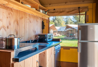Área de cocina en la tienda Safari Comfort en Papillon Country Resort, con electrodomésticos y vista exterior.