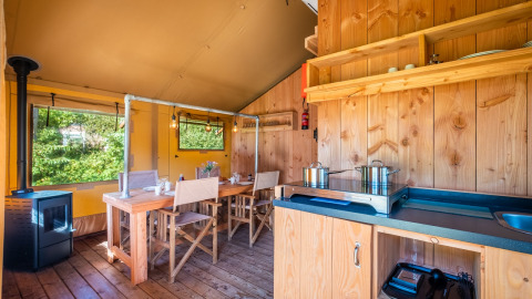 Interior de la Safari tent Comfort en Papillon Country Resort, Países Bajos, con comedor y cocina básica visibles.