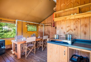 Interior de la Safari tent Comfort en Papillon Country Resort, Países Bajos, con comedor y cocina básica visibles.