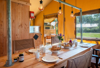 Interior of Safari Tent Comfort at Papillon Country Resort, Netherlands, with dining table set for breakfast.
