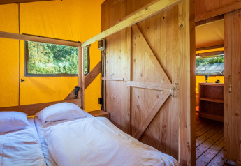 Soveværelse i Safari tent Comfort på Papillon Country Resort i Holland med trævægge og gult teltstof.