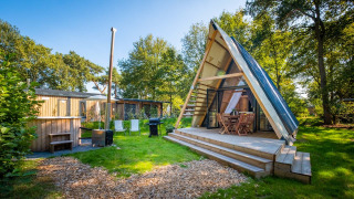 Tiny house Luxury Hottub Cabin avec structure en A, terrasse bois et jacuzzi dans un jardin verdoyant.