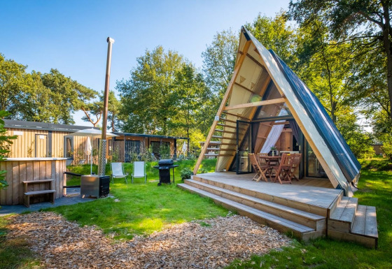 Casa pequeña Luxury Hottub Cabin con estructura en A, terraza de madera y jacuzzi en jardín verde.