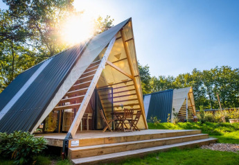 Moderne A-formet tiny house på Papillon Country Resort i Holland med træterrasse og morgensol.