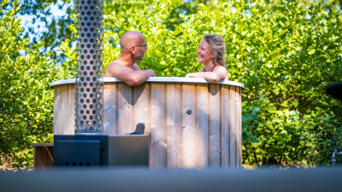 Pareja disfruta de bañera de hidromasaje de madera en Luxury Hottub Cabin de Papillon Country Resort, Países Bajos.