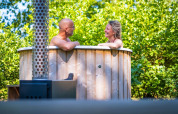 Pareja disfruta de bañera de hidromasaje de madera en Luxury Hottub Cabin de Papillon Country Resort, Países Bajos.