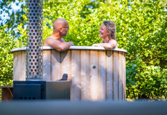 Couple se détend dans un bain nordique extérieur à la Luxury Hottub Cabin du Papillon Country Resort, Pays-Bas.