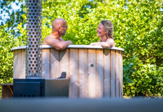 Pareja disfruta de bañera de hidromasaje de madera en Luxury Hottub Cabin de Papillon Country Resort, Países Bajos.