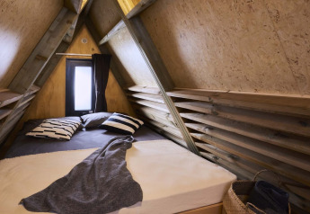 Soveområde i en lille cabine med A-ramme, trævægge og vindue på Papillon Country Resort i Holland.