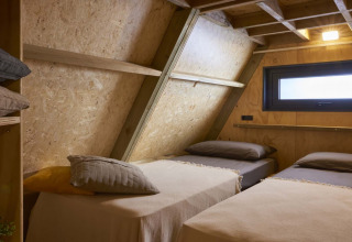 Chambre chaleureuse avec deux lits simples dans une tiny house au Papillon Country Resort, Pays-Bas.
