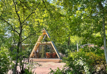 Una pequeña cabaña de lujo en forma de A con terraza de madera en Papillon Country Resort, Países Bajos.